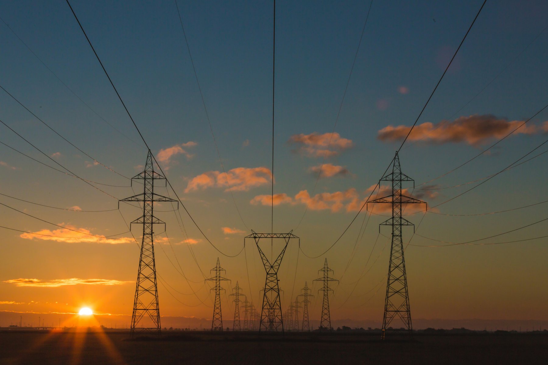 The sun setting behind a trio of power lines