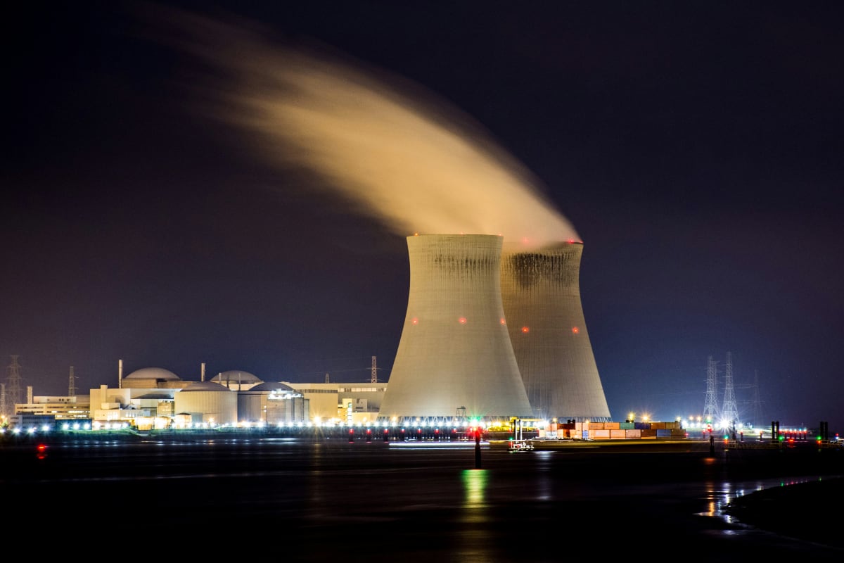 A power plant at night, with the lights of surrounding buildings