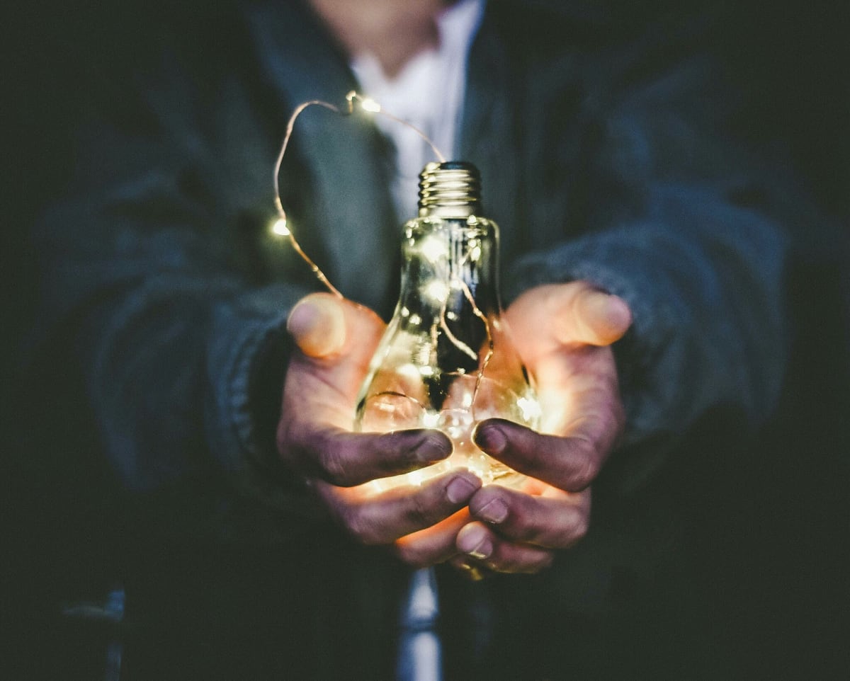 A man holding a lightbulb in outstretched hands